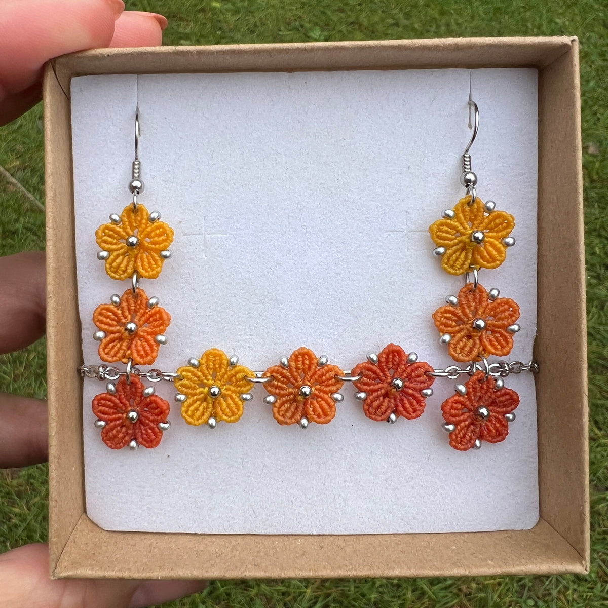 Boucles d’oreilles et bracelet  Blossom en micro-macramé aux couleurs de l’automne, trois fleurs jaune Soleil, orange clair Topaz et orange foncé, avec perles argentées, création artisanale Macram’Elo Créations.

