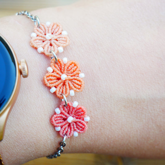 Bracelet Blossom orné de trois fleurs en micro-macramé en camaïeu de Corail sur chaîne perlée argentée, bijou fleuri fait main par Macram’Elo Créations.