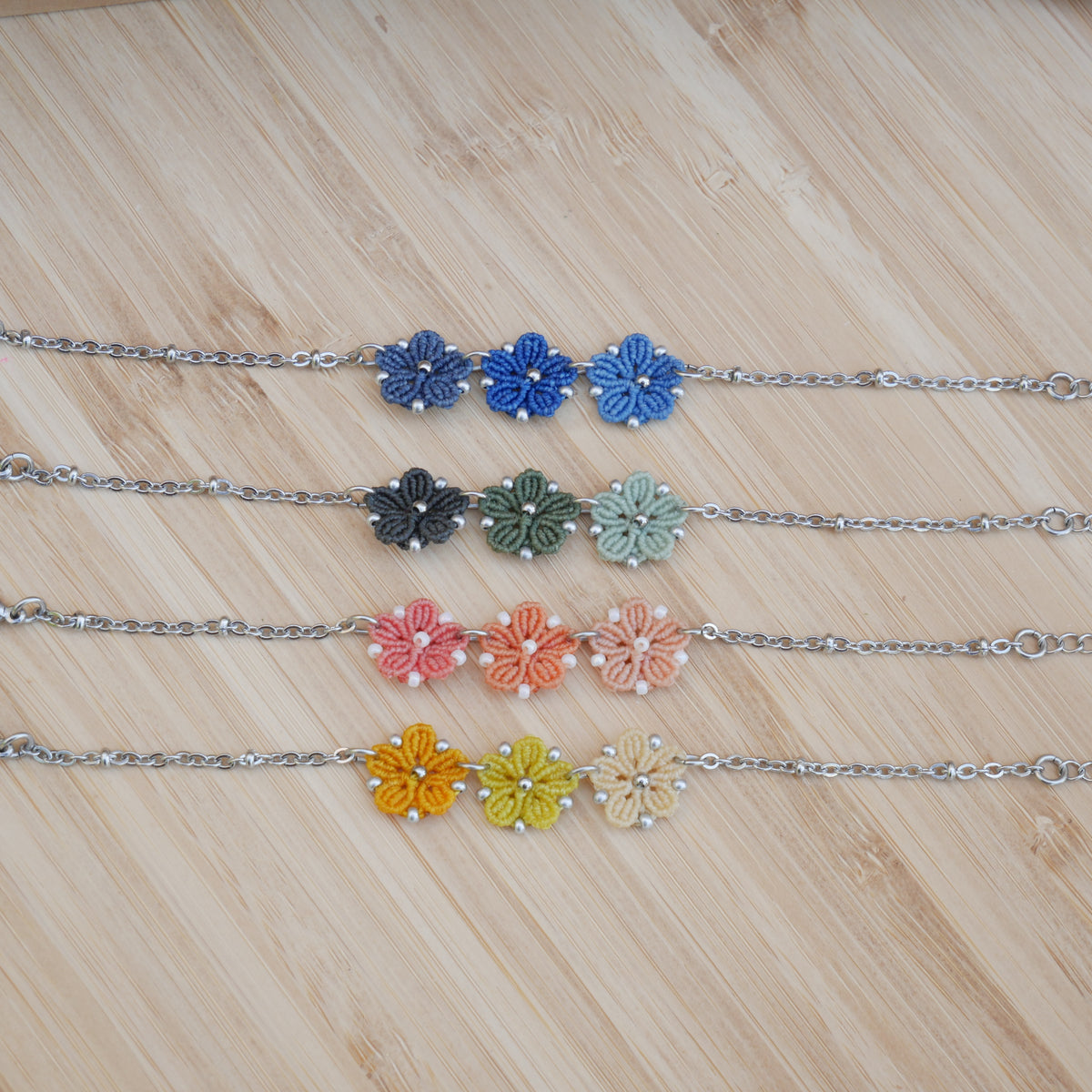 Bracelet Blossom orné de trois fleurs en micro-macramé en camaïeu de couleurs assorties sur chaîne perlée argentée, bijou fleuri fait main par Macram’Elo Créations.