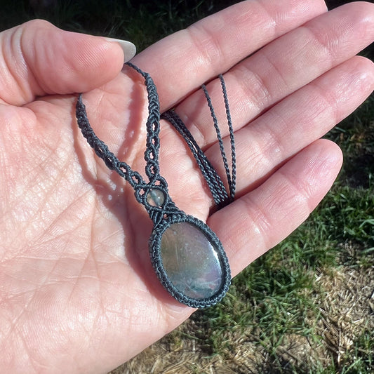 Un collier tissé en micro-macramé gris foncé avec un cabochon oval et une perle une pierre naturelle d'Agate mousse