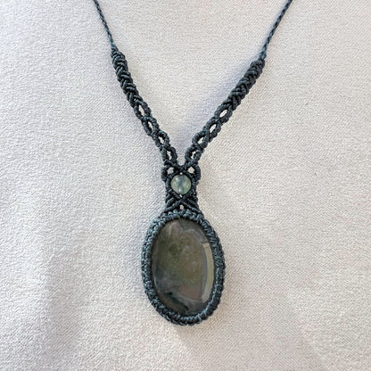 Un collier tissé en micro-macramé gris foncé avec un cabochon oval et une perle une pierre naturelle d'Agate mousse